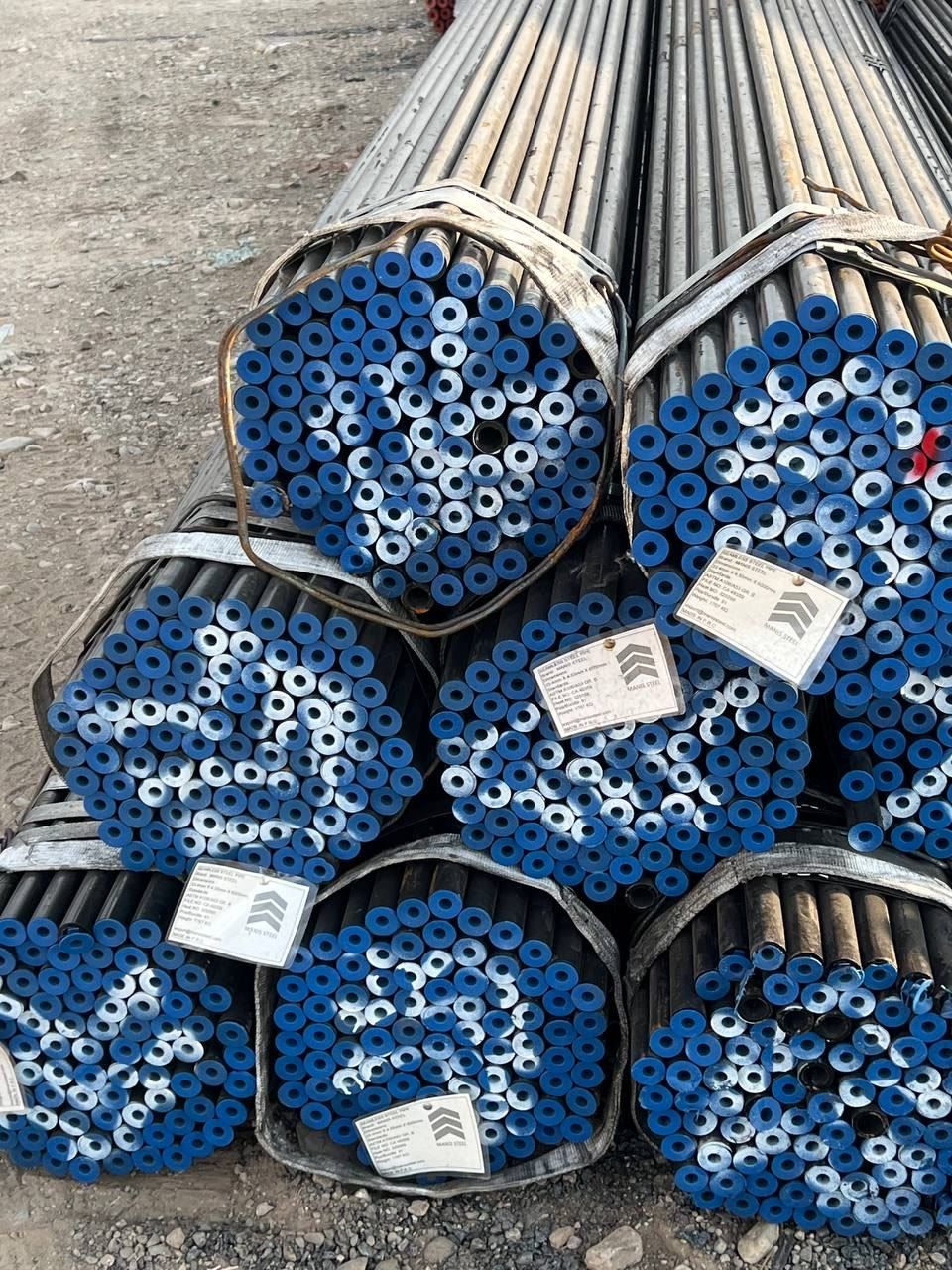 Hexagonal bundles of small-diameter pipe with blue end caps and Manis Steel tags