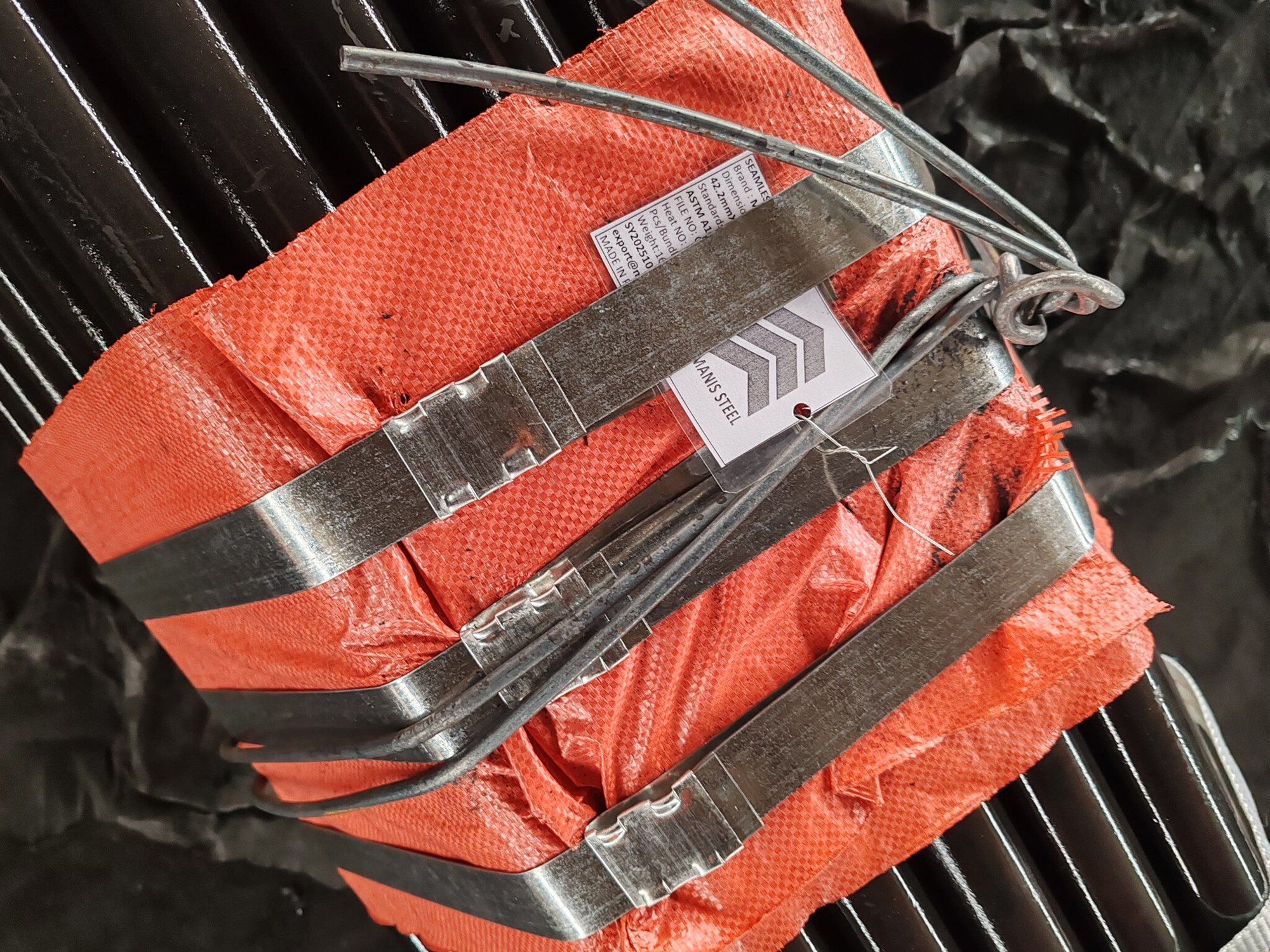Bundle of 42.2 mm seamless pipes in woven wrapping with steel straps and a Manis Steel tag