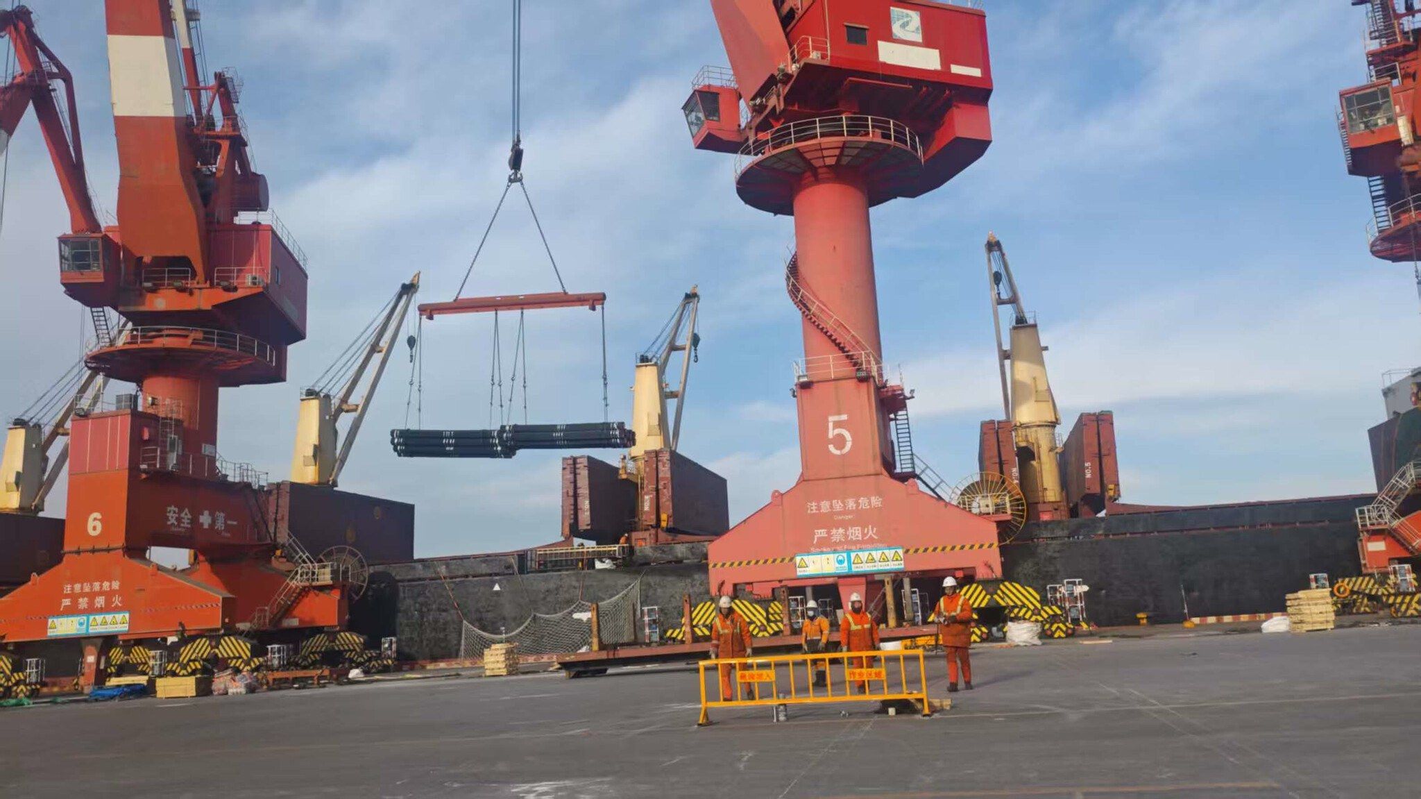 Port gantry cranes lifting a bundle of seamless pipe at the port of loading