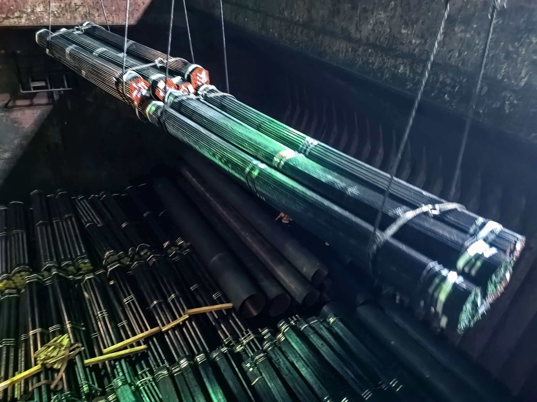 A bundle of seamless pipe being lowered onto stowed pipe in a ship’s hold